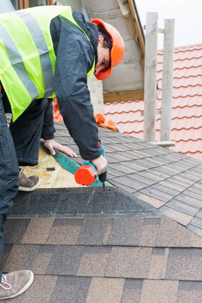 Roofer builder worker dismantling roof shingles